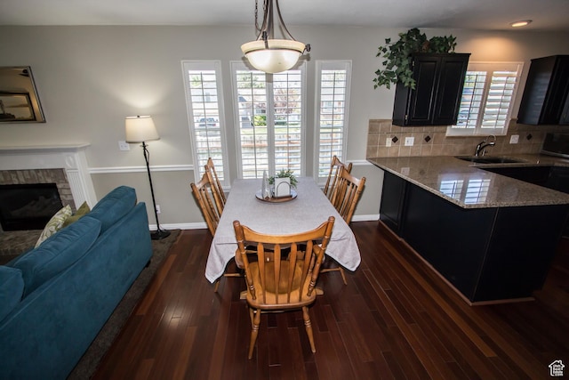 dining space featuring dark wood-type flooring, a fireplace, baseboards, and recessed lighting