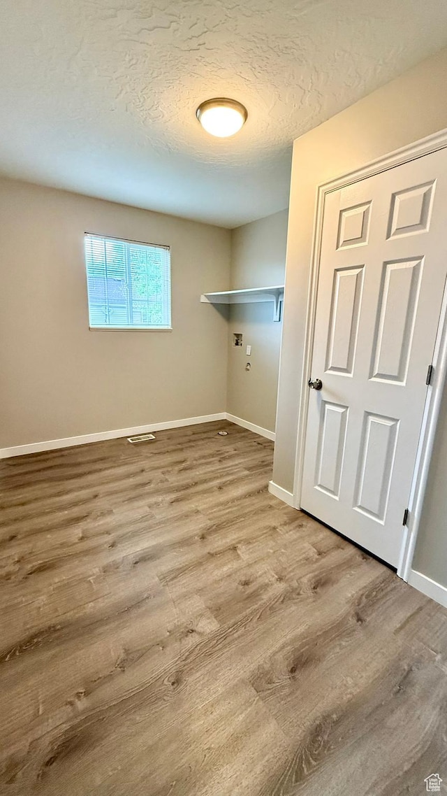 laundry area featuring wood finished floors, a textured ceiling, baseboards, and washer hookup