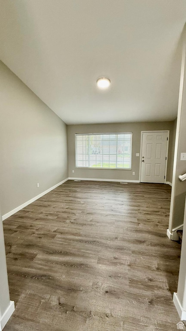 unfurnished living room with baseboards and wood finished floors