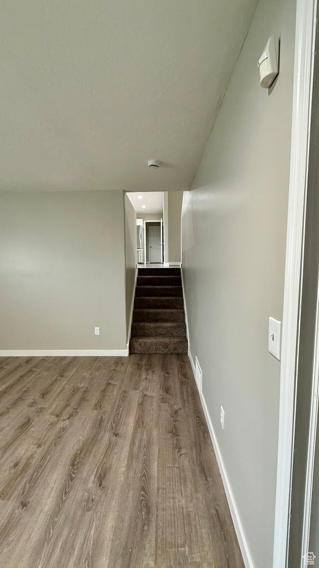 staircase featuring wood finished floors and baseboards