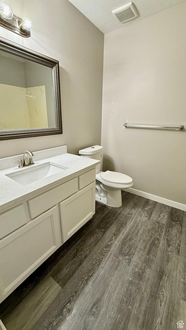 bathroom featuring wood finished floors, toilet, vanity, and baseboards