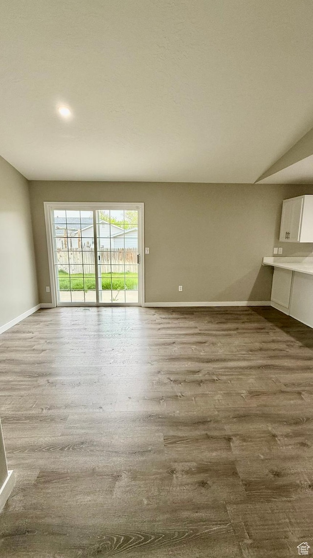 unfurnished living room with dark wood finished floors and baseboards