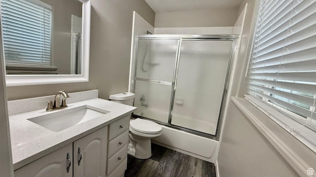 full bathroom featuring wood finished floors, combined bath / shower with glass door, toilet, and vanity
