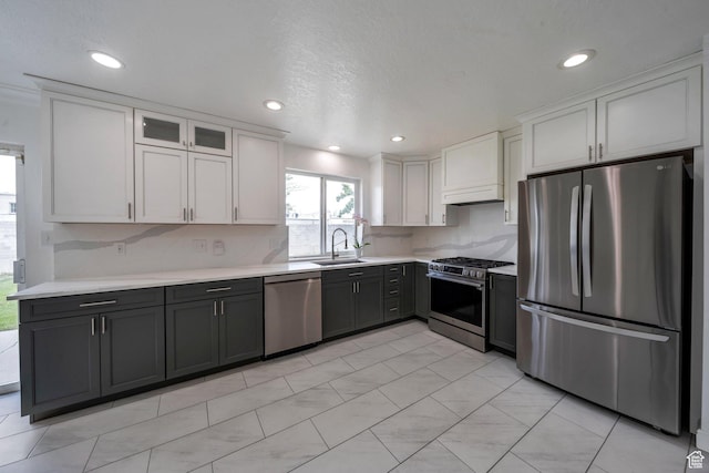 kitchen with stainless steel appliances, a sink, light countertops, backsplash, and recessed lighting