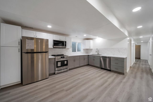 kitchen with stainless steel appliances, gray cabinetry, light wood-type flooring, light countertops, and recessed lighting