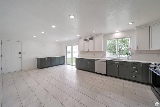 kitchen with appliances with stainless steel finishes, a sink, plenty of natural light, light countertops, and recessed lighting