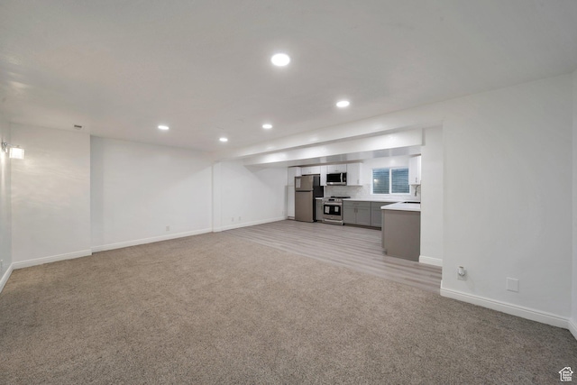 unfurnished living room with light carpet, baseboards, and recessed lighting