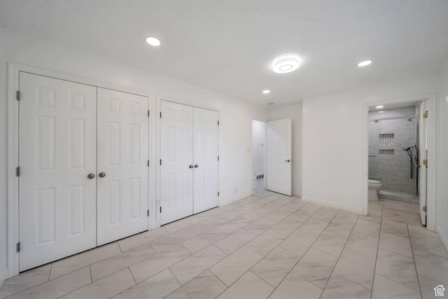 unfurnished bedroom with two closets, baseboards, ensuite bathroom, and recessed lighting