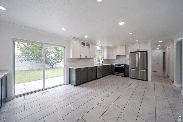 kitchen with appliances with stainless steel finishes, light countertops, white cabinets, crown molding, and recessed lighting