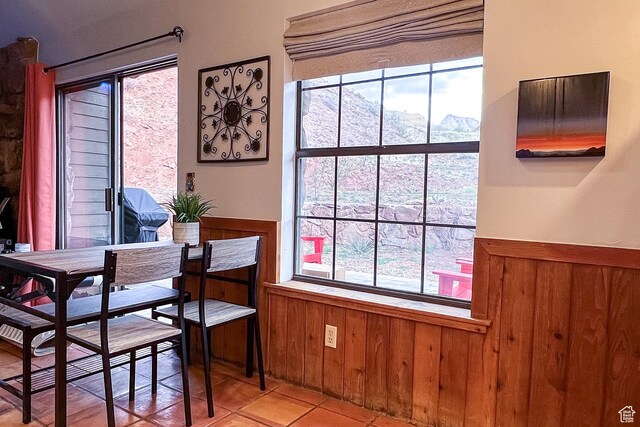 dining space featuring a wainscoted wall, light tile patterned floors, a mountain view, and wood walls