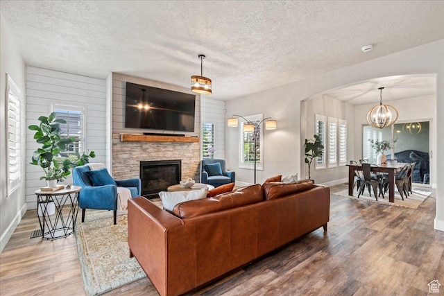 5153 W Bowstring Way S, Jordan, UT 84009 - living area with a stone fireplace, wood finished floors, a textured ceiling, baseboards, and a chandelier
