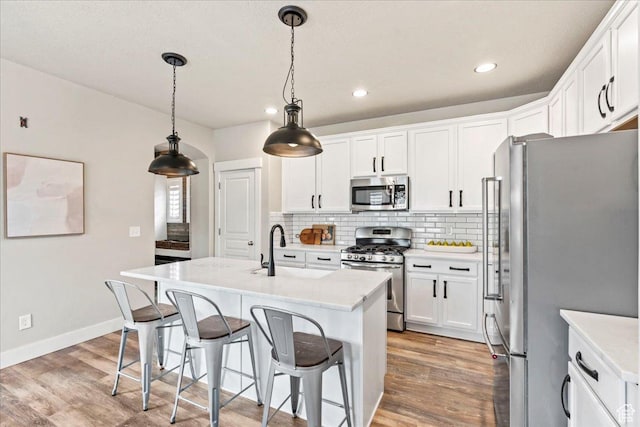 5153 W Bowstring Way S, Jordan, UT 84009 - kitchen featuring appliances with stainless steel finishes, light wood-type flooring, decorative backsplash, white cabinetry, and recessed lighting