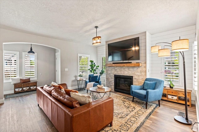 5153 W Bowstring Way S, Jordan, UT 84009 - living room with wood finished floors, a textured ceiling, a fireplace, arched walkways, and baseboards