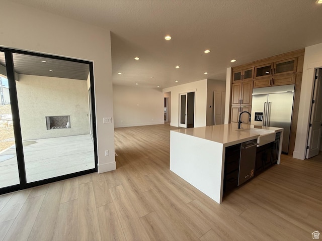 kitchen featuring appliances with stainless steel finishes, light wood-type flooring, brown cabinetry, recessed lighting, and light countertops