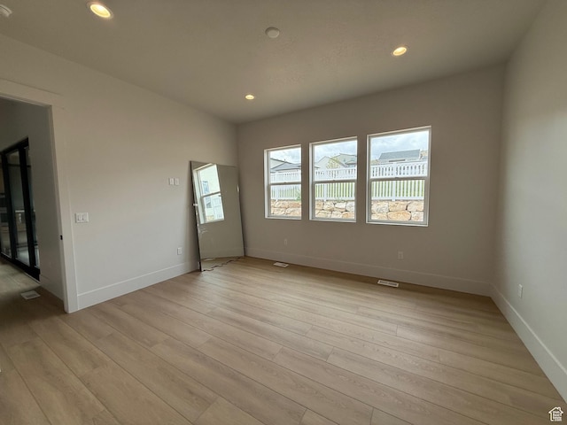 empty room with light wood finished floors, baseboards, and recessed lighting