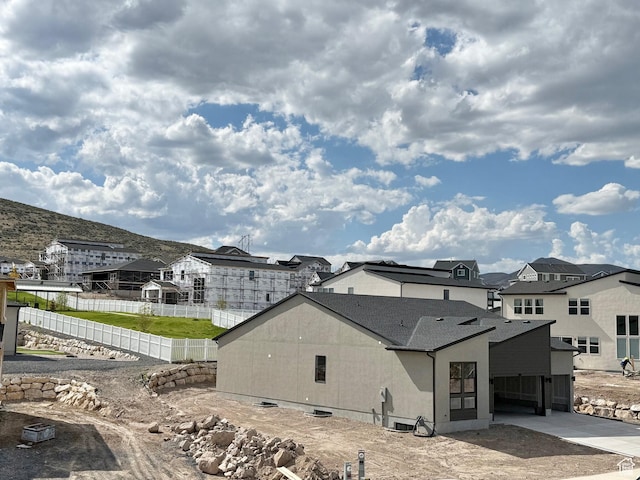 back of house featuring fence, a residential view, concrete driveway, and a mountain view