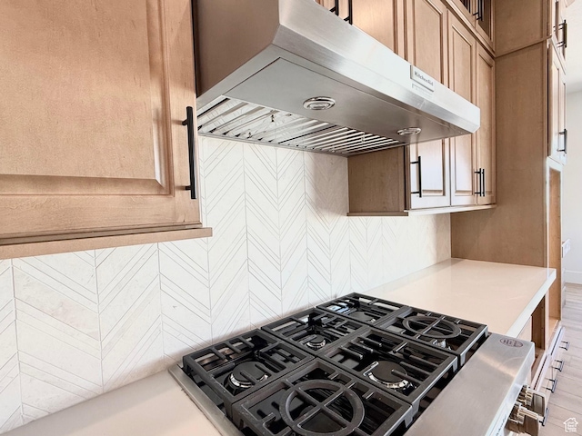 kitchen featuring extractor fan, light countertops, decorative backsplash, cooktop, and baseboards