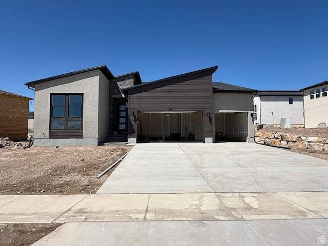 contemporary home with a garage, concrete driveway, and stucco siding