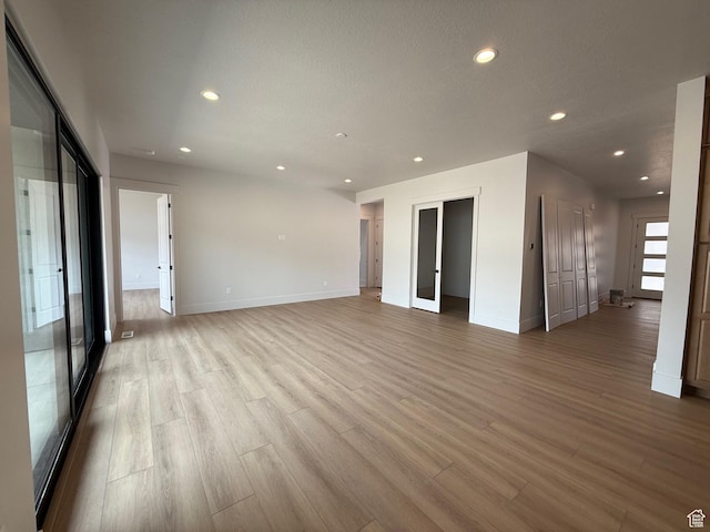 unfurnished room with light wood-type flooring, recessed lighting, and baseboards