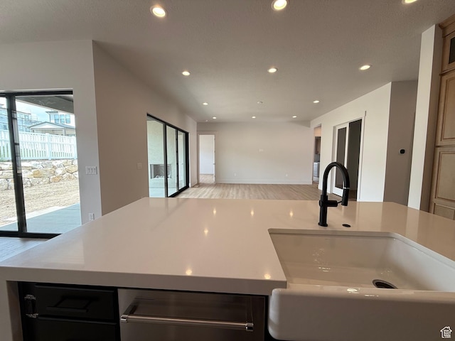 kitchen with a sink, recessed lighting, light wood-style flooring, open floor plan, and light countertops