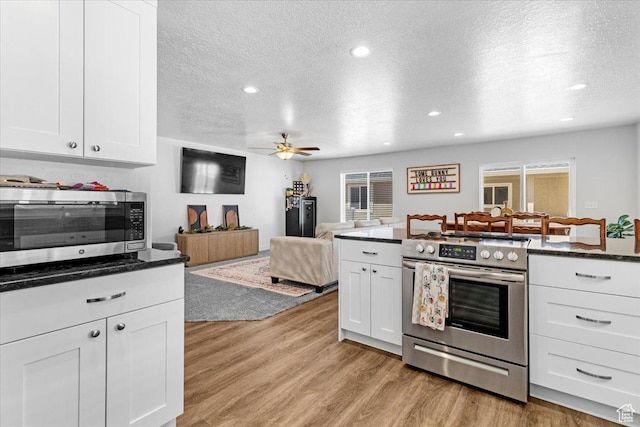 kitchen with stainless steel appliances, a textured ceiling, white cabinetry, light wood-type flooring, and recessed lighting