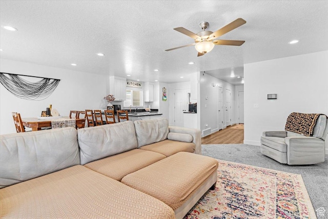 living room featuring recessed lighting, ceiling fan, a textured ceiling, baseboards, and light colored carpet