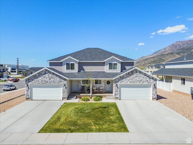 view of front facade with stone siding, concrete driveway, covered porch, a shingled roof, and a mountain view