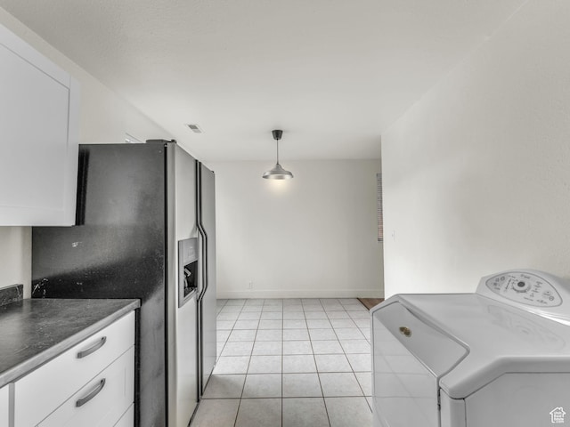 kitchen featuring washer / clothes dryer, stainless steel fridge, white cabinetry, dark countertops, and light tile patterned floors