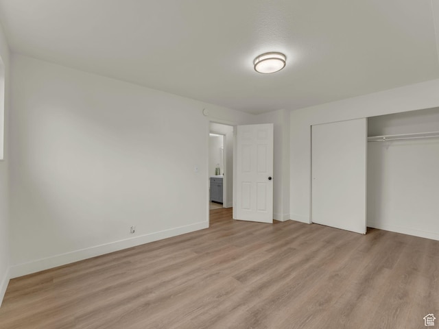 unfurnished bedroom with light wood-style flooring, a closet, and baseboards