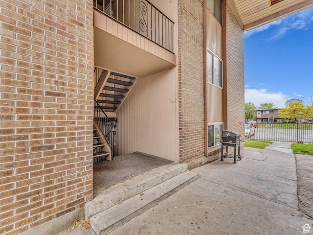 doorway to property with brick siding and fence