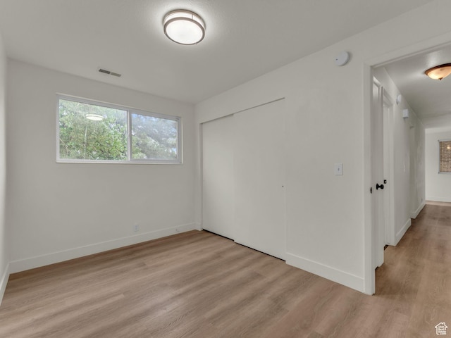 unfurnished bedroom with light wood-type flooring, a closet, and baseboards