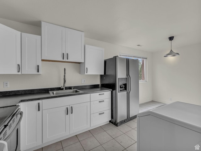 kitchen with appliances with stainless steel finishes, a sink, white cabinetry, hanging light fixtures, and dark countertops