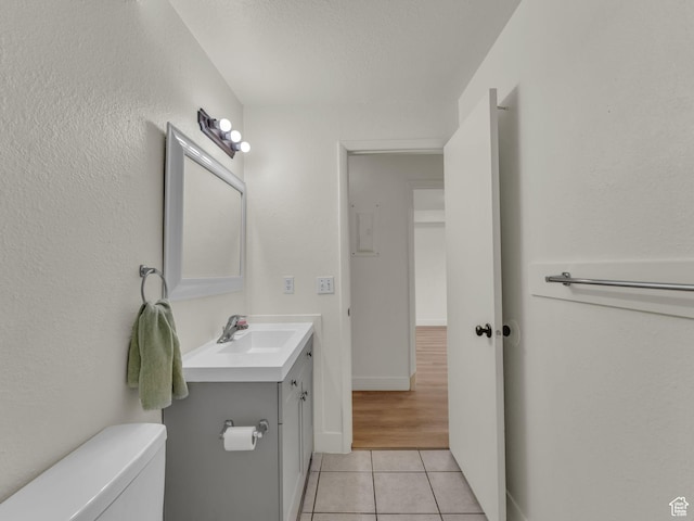 half bath featuring tile patterned floors, vanity, toilet, and baseboards