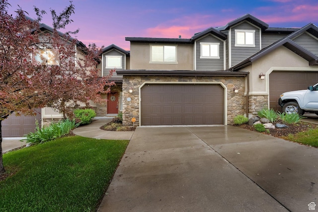 view of property featuring stone siding, stucco siding, driveway, and an attached garage