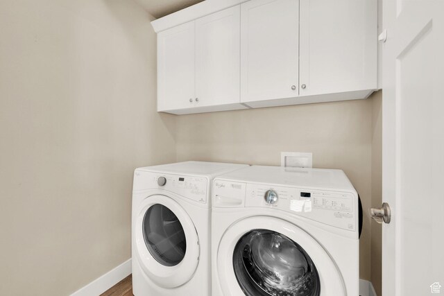 clothes washing area with cabinet space, washer and dryer, and baseboards
