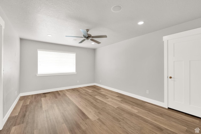 empty room with a ceiling fan, wood finished floors, baseboards, recessed lighting, and a textured ceiling