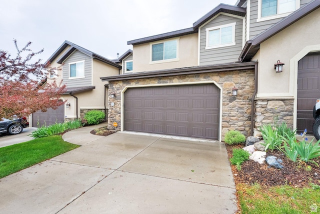 view of front facade featuring stone siding, stucco siding, an attached garage, and driveway