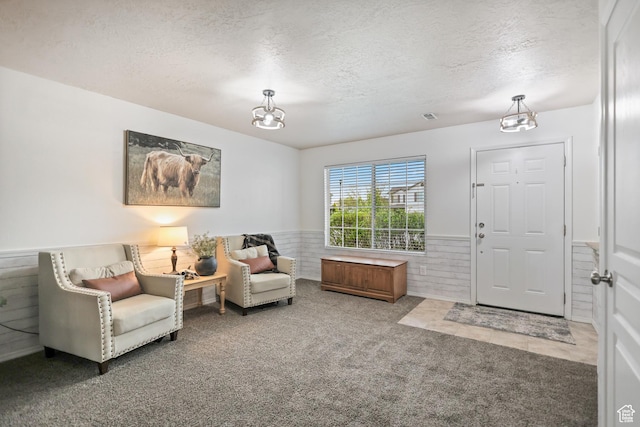sitting room with a wainscoted wall, a textured ceiling, carpet floors, and a chandelier