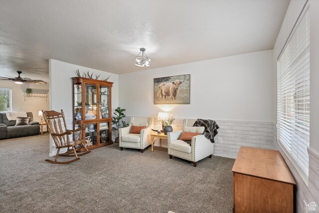 carpeted living room featuring a ceiling fan and wainscoting