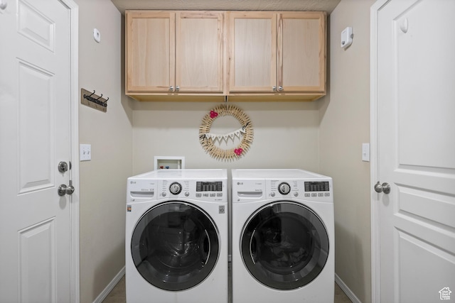 washroom with cabinet space, washing machine and dryer, and baseboards