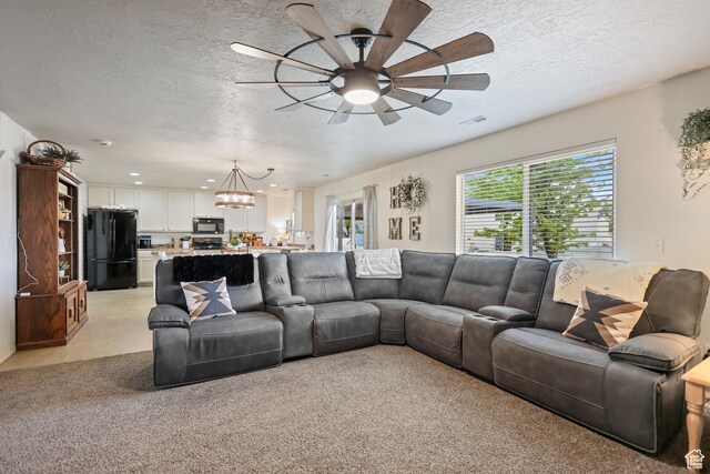 living area featuring a chandelier, a ceiling fan, and a textured ceiling