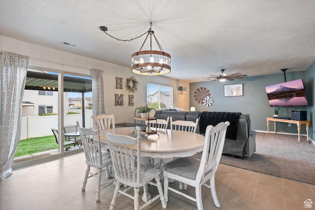 tiled dining area with a textured ceiling, ceiling fan, a chandelier, and baseboards