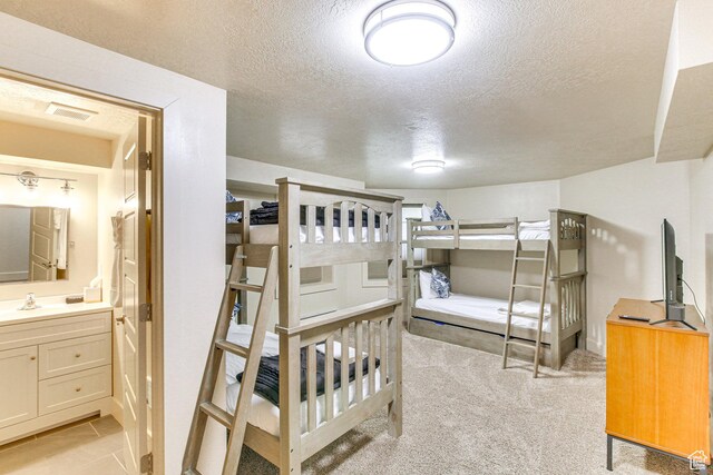 40 N Christa Cir, Garden City, UT 84028 - bedroom featuring a textured ceiling, light colored carpet, ensuite bathroom, and a sink