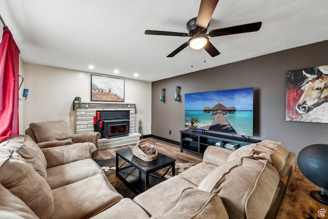 living room featuring a ceiling fan, wood finished floors, recessed lighting, a stone fireplace, and baseboards