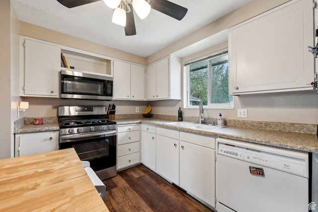 kitchen with stainless steel appliances, a sink, ceiling fan, dark wood-style floors, and white cabinets