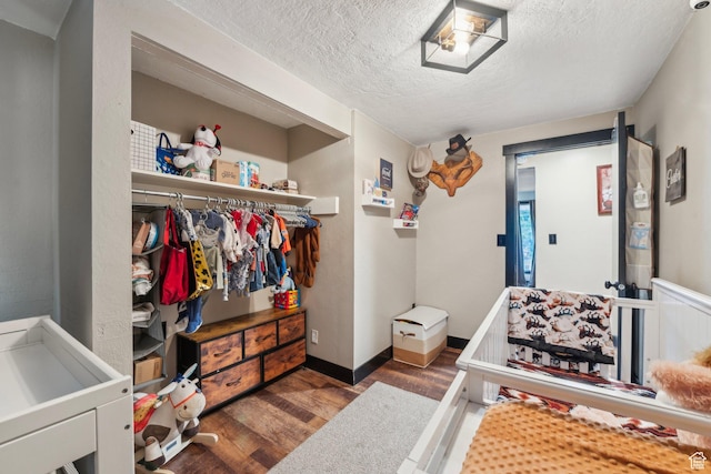 bedroom featuring wood finished floors, a textured ceiling, and baseboards