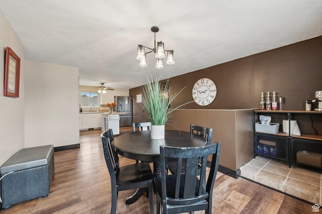 dining area featuring wood finished floors, a chandelier, ceiling fan, and baseboards
