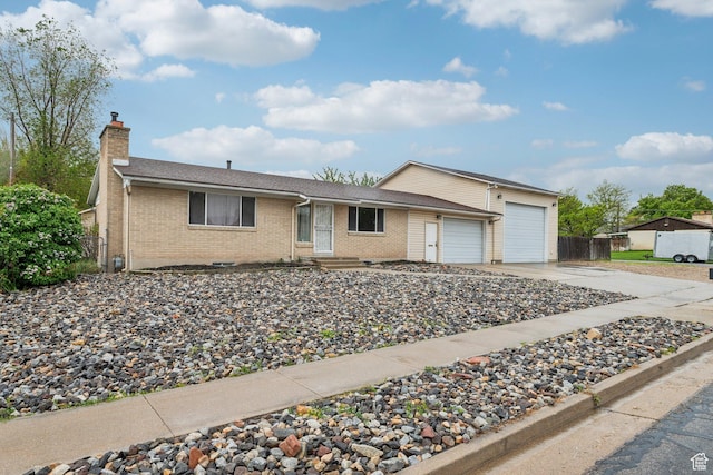 ranch-style home with a chimney, brick siding, a garage, concrete driveway, and fence
