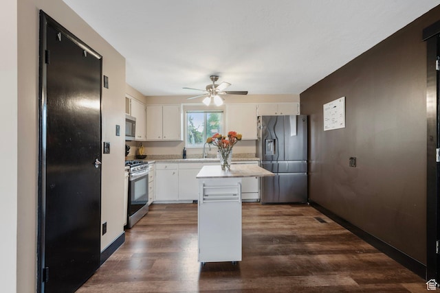kitchen featuring appliances with stainless steel finishes, light countertops, a sink, a center island, and ceiling fan