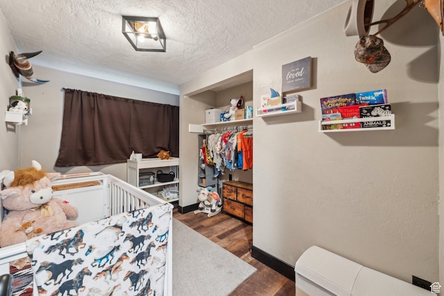 bedroom featuring wood finished floors, a textured ceiling, a closet, and baseboards
